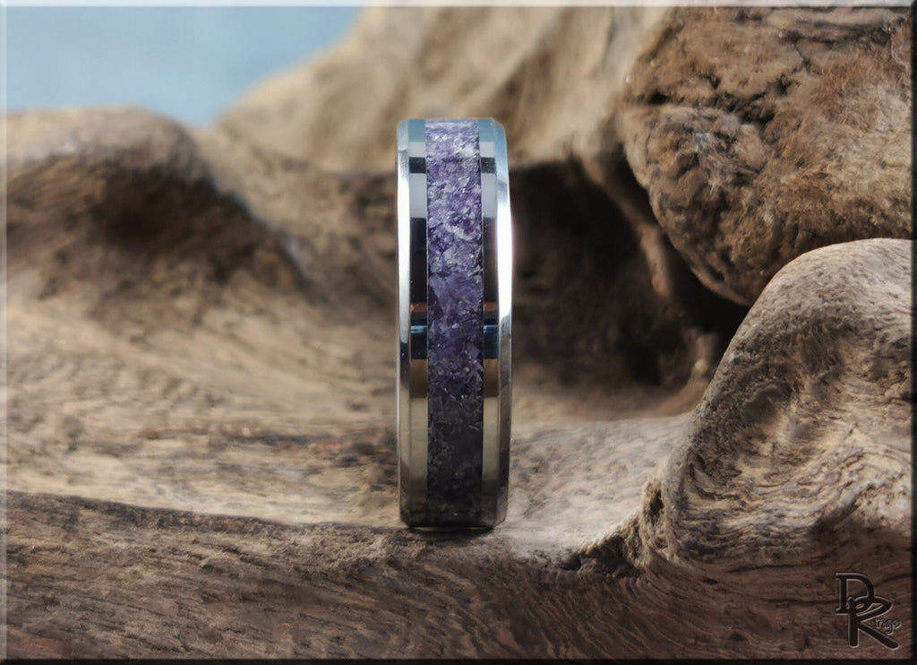 Tungsten ring with amethyst purple stone inlay on a textured natural wood background