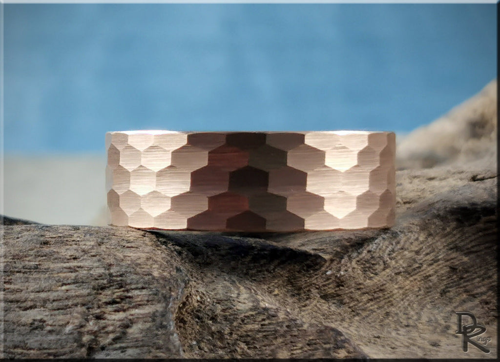 Tungsten ring with wood liner featuring a hammered rose gold finish by DR Rings displayed on rustic wood
