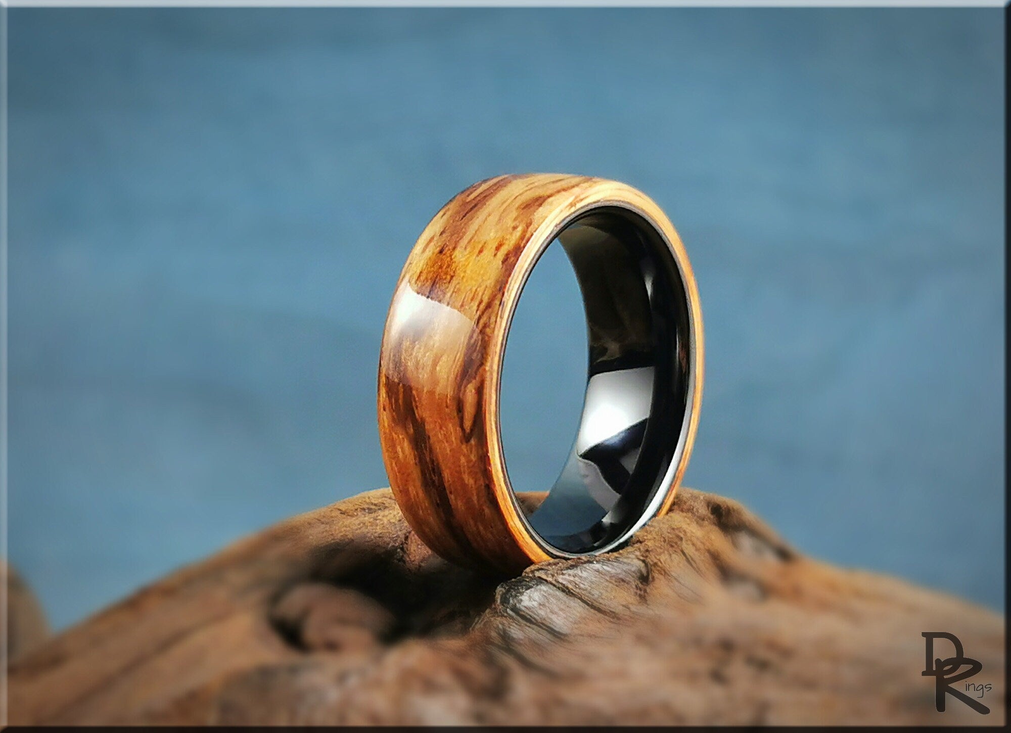 Wood ring on ceramic core with natural wood grain finish from DR Rings displayed on rustic wood