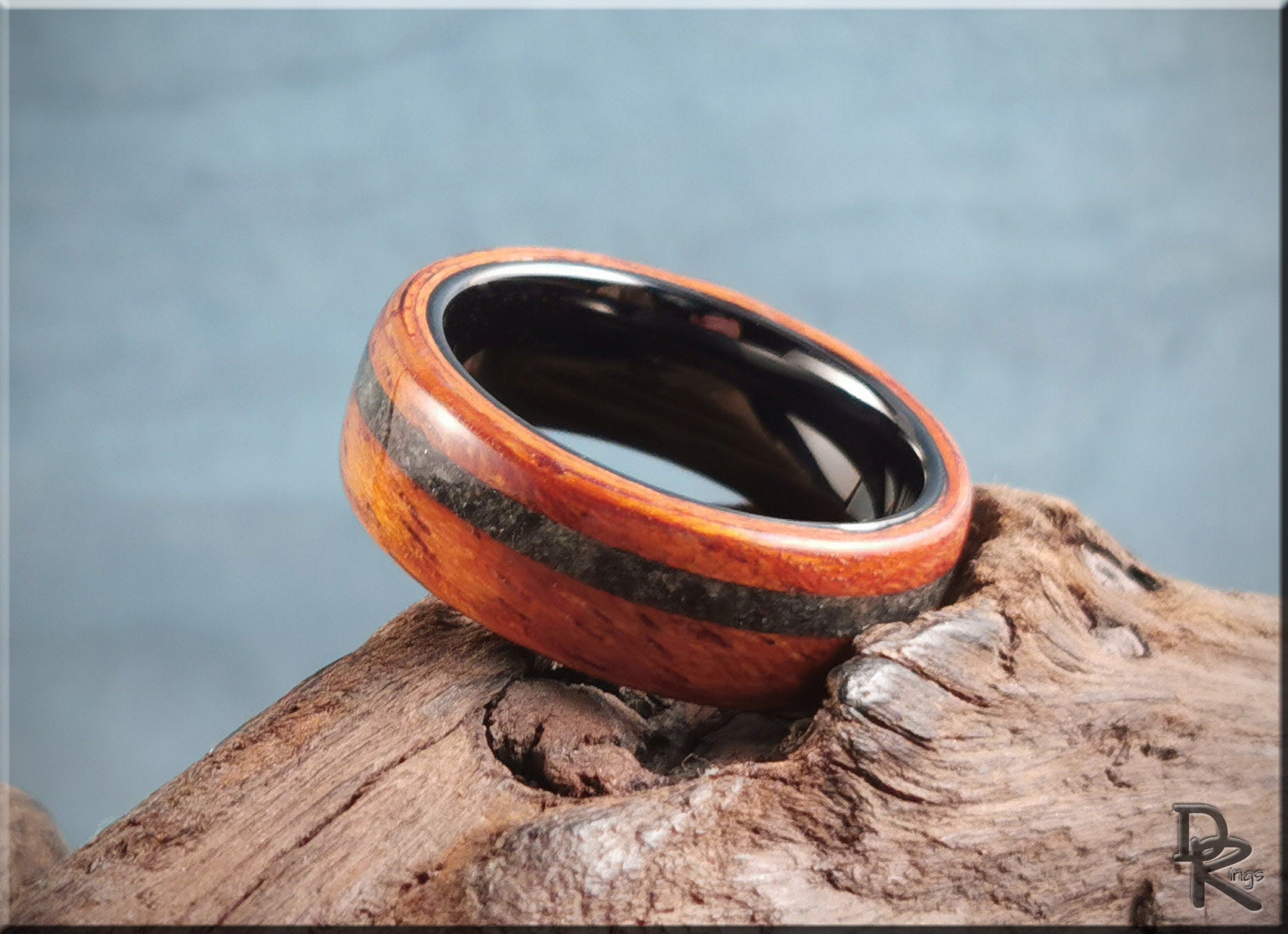 Wood ring with inlay featuring polished wood and black inner band on natural wooden surface