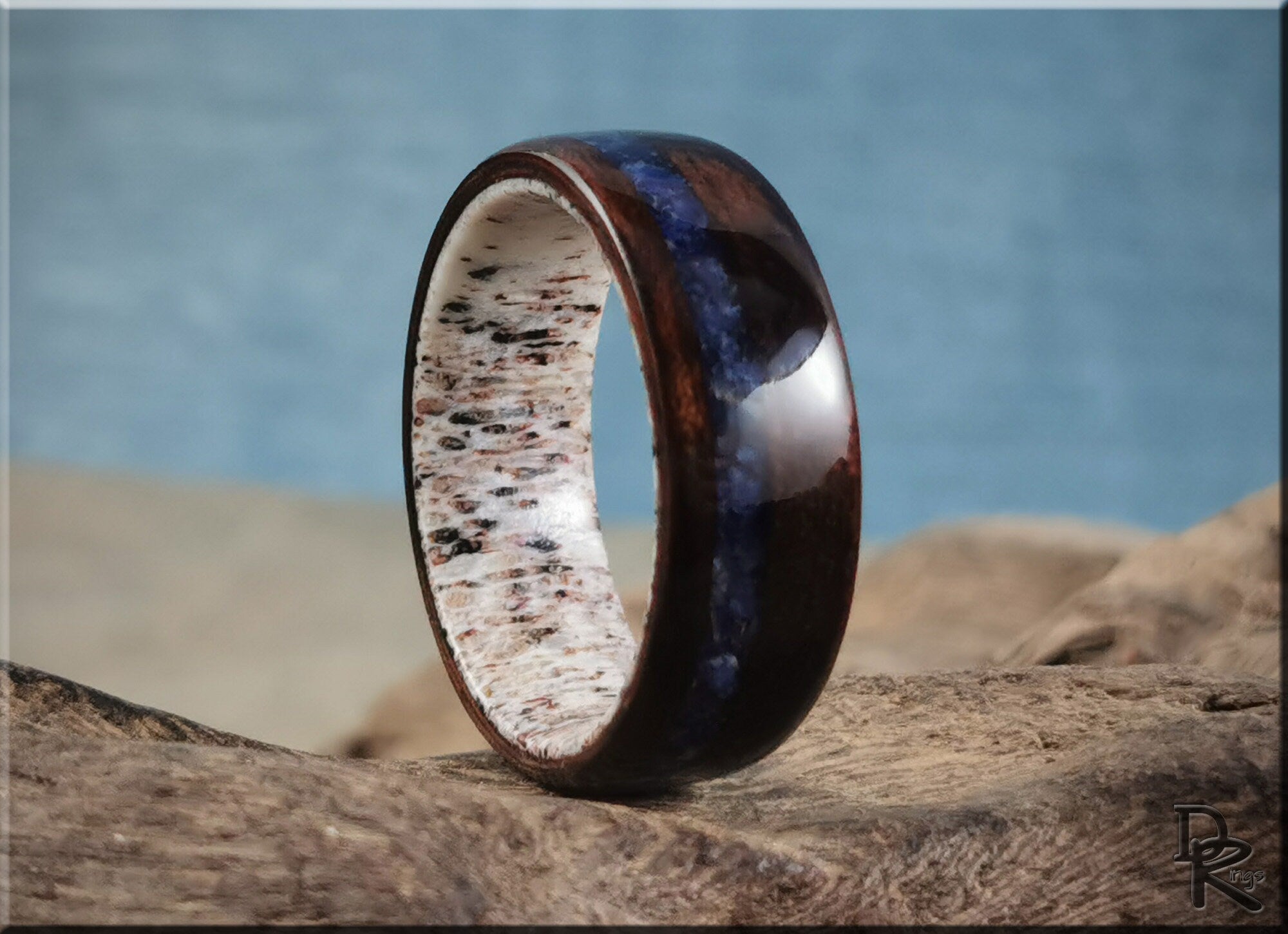 DR Rings wood ring with inlay featuring dark wood and blue stone on a textured surface