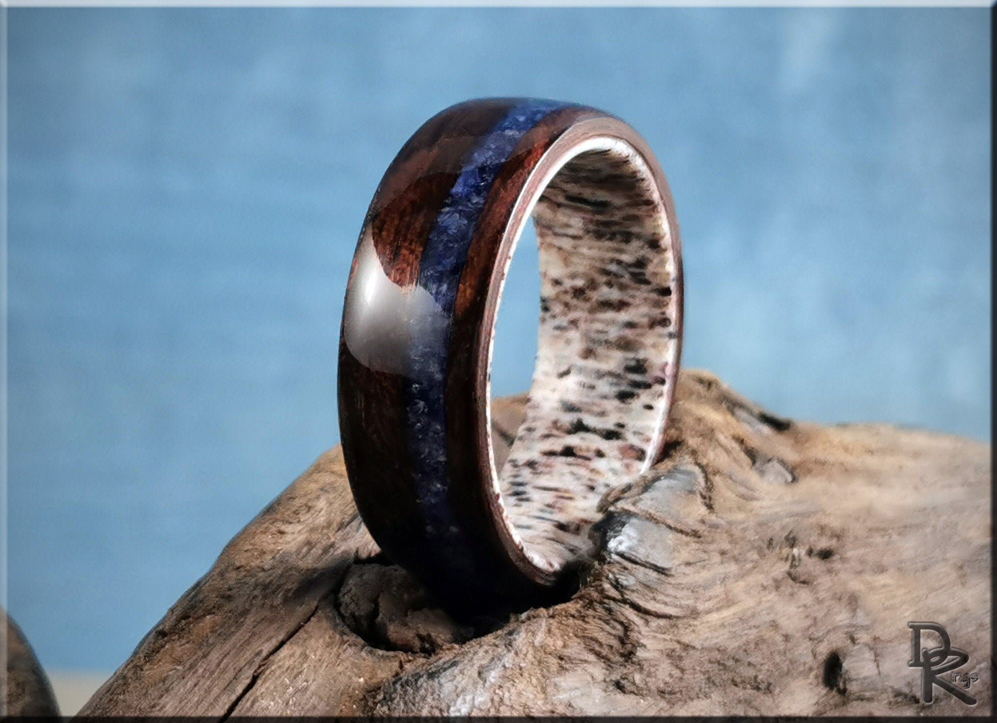 Wood ring with inlay featuring dark brown wood and blue stone on a textured wooden surface