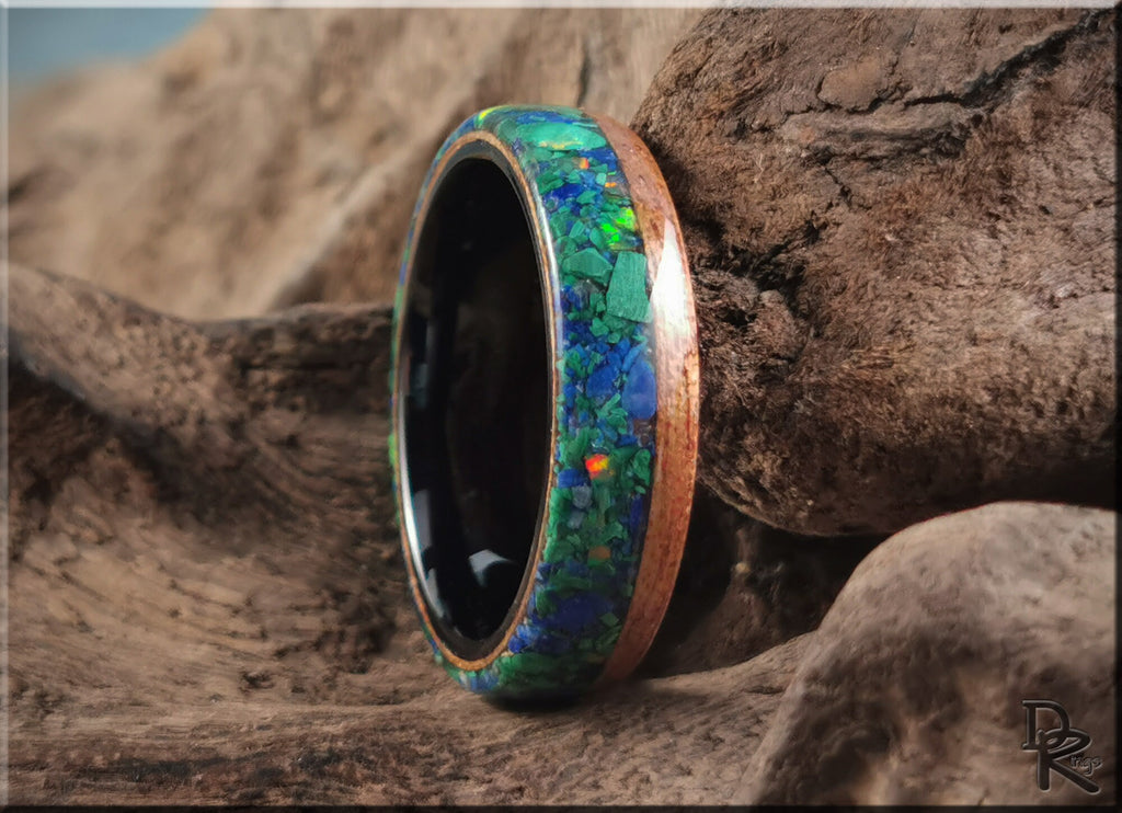 Wood ring with malachite inlay featuring vibrant green and blue tones on natural wood grain background