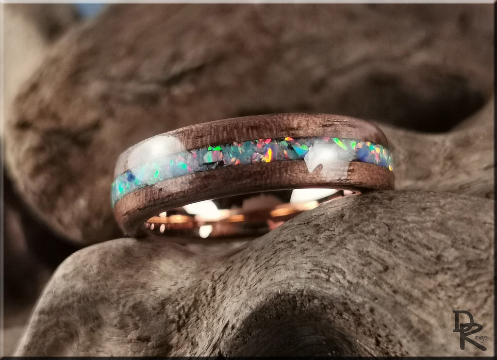 Wood ring with opal inlay by DR Rings resting on textured wood background