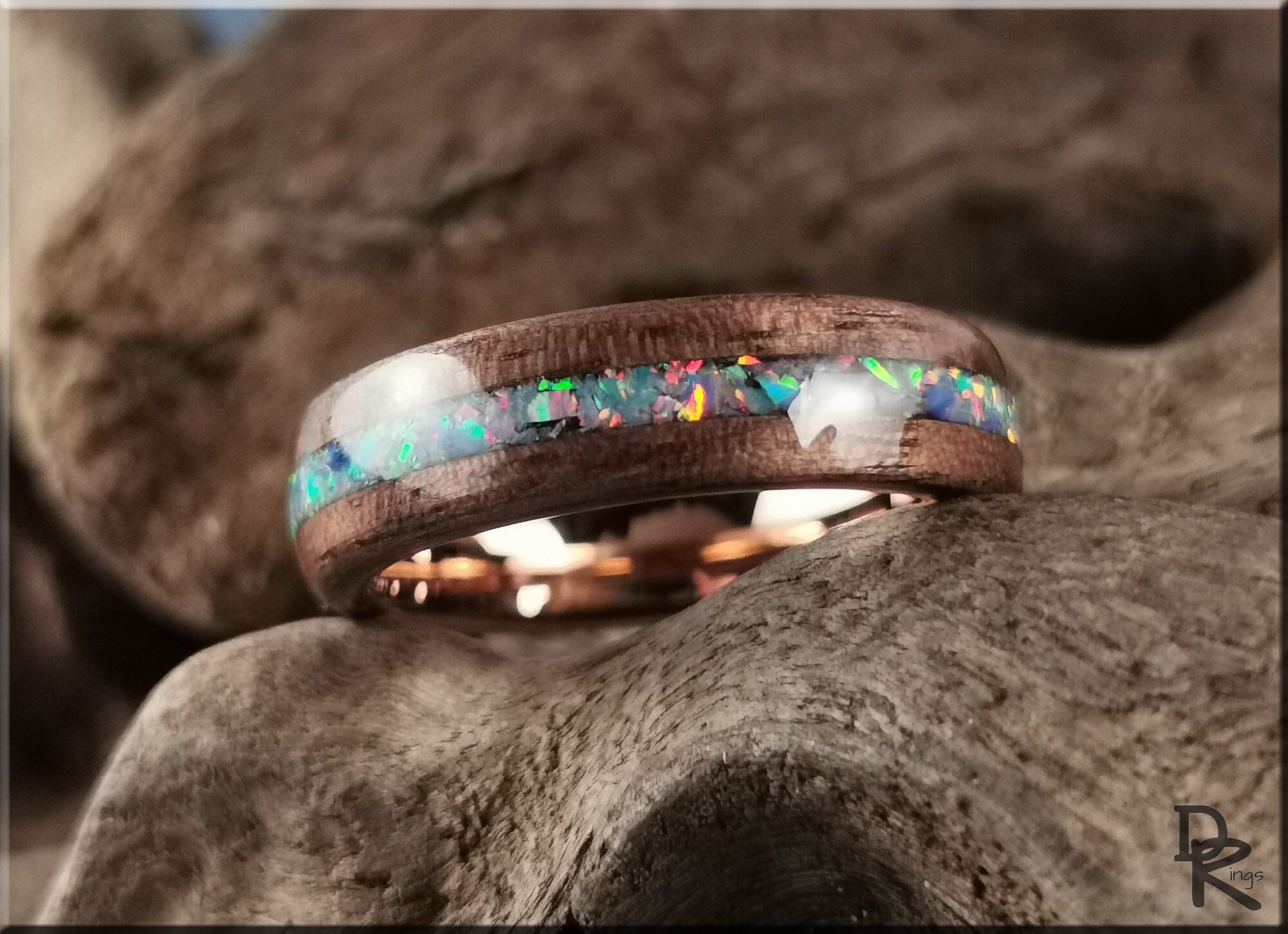 Wood ring with opal inlay by DR Rings resting on textured wood background