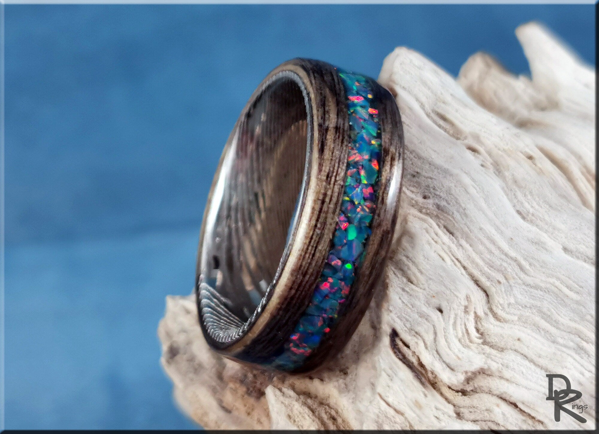 DR Rings wood ring with opal inlay featuring colorful blue and red stones on natural wood background