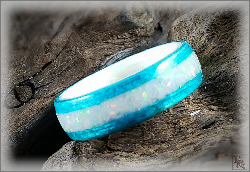 DR Rings wood ring with opal inlay featuring vibrant blue edges and iridescent white center on rustic wood background