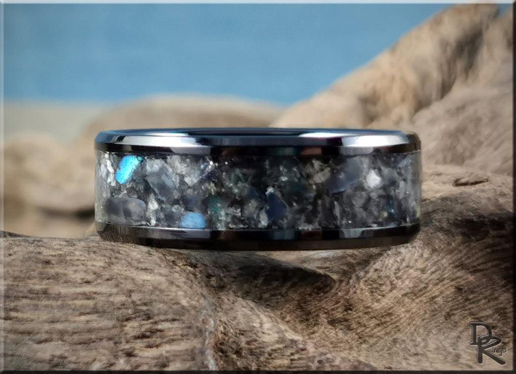 Black ceramic ring with inlay featuring a unique textured design on a natural wooden surface