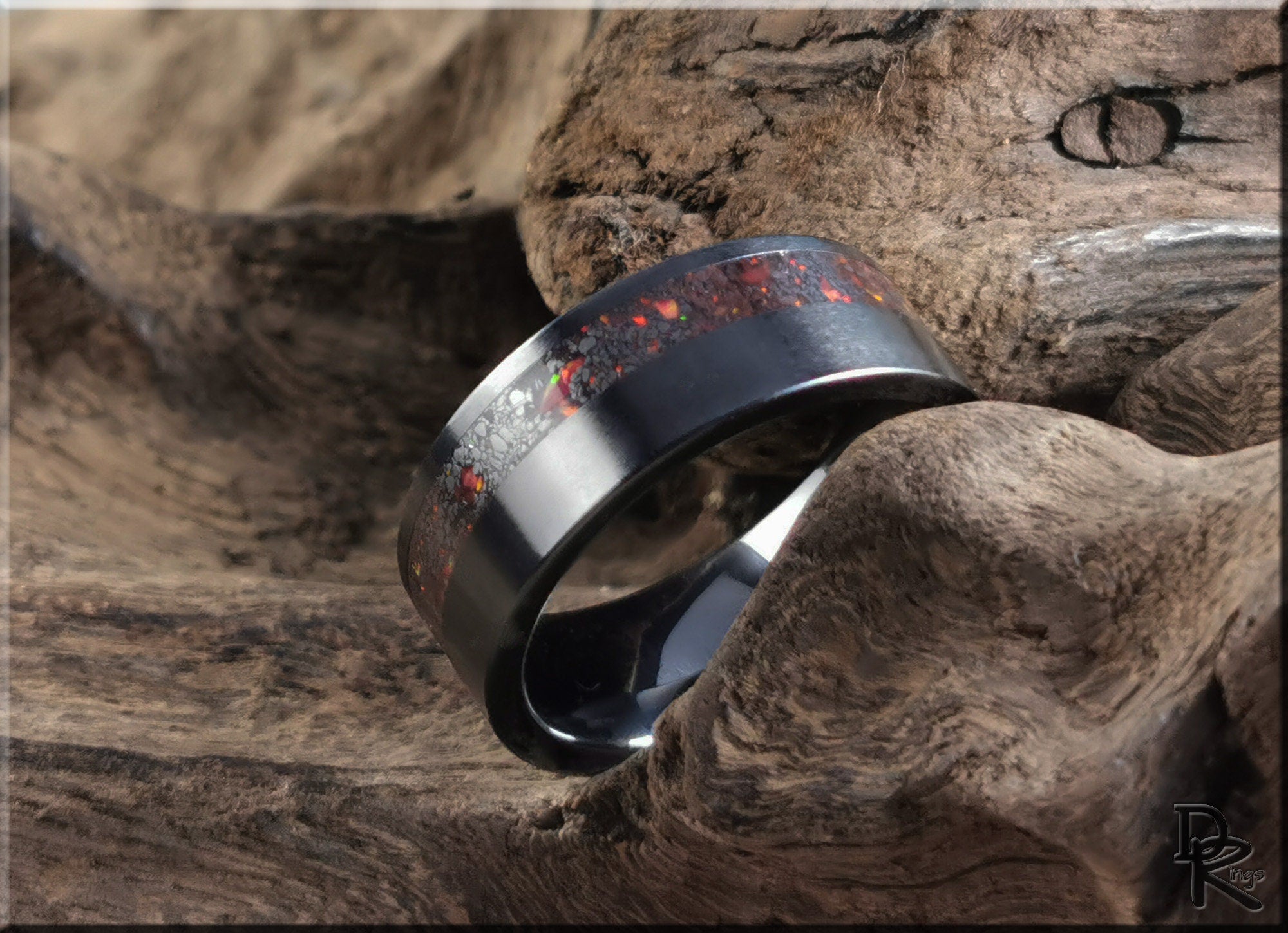 DR Rings black band ring opal inlay with red and orange flecks on rustic wooden background