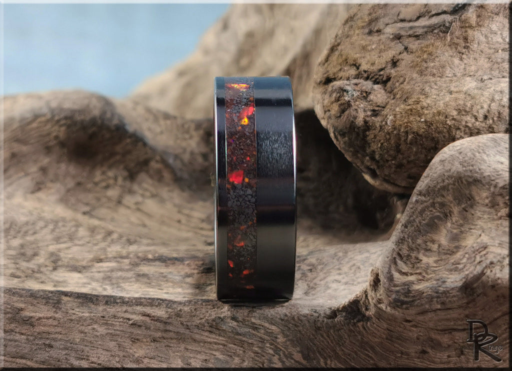 Black ring with red and orange accents featuring a ring opal design by DR Rings displayed on natural wood
