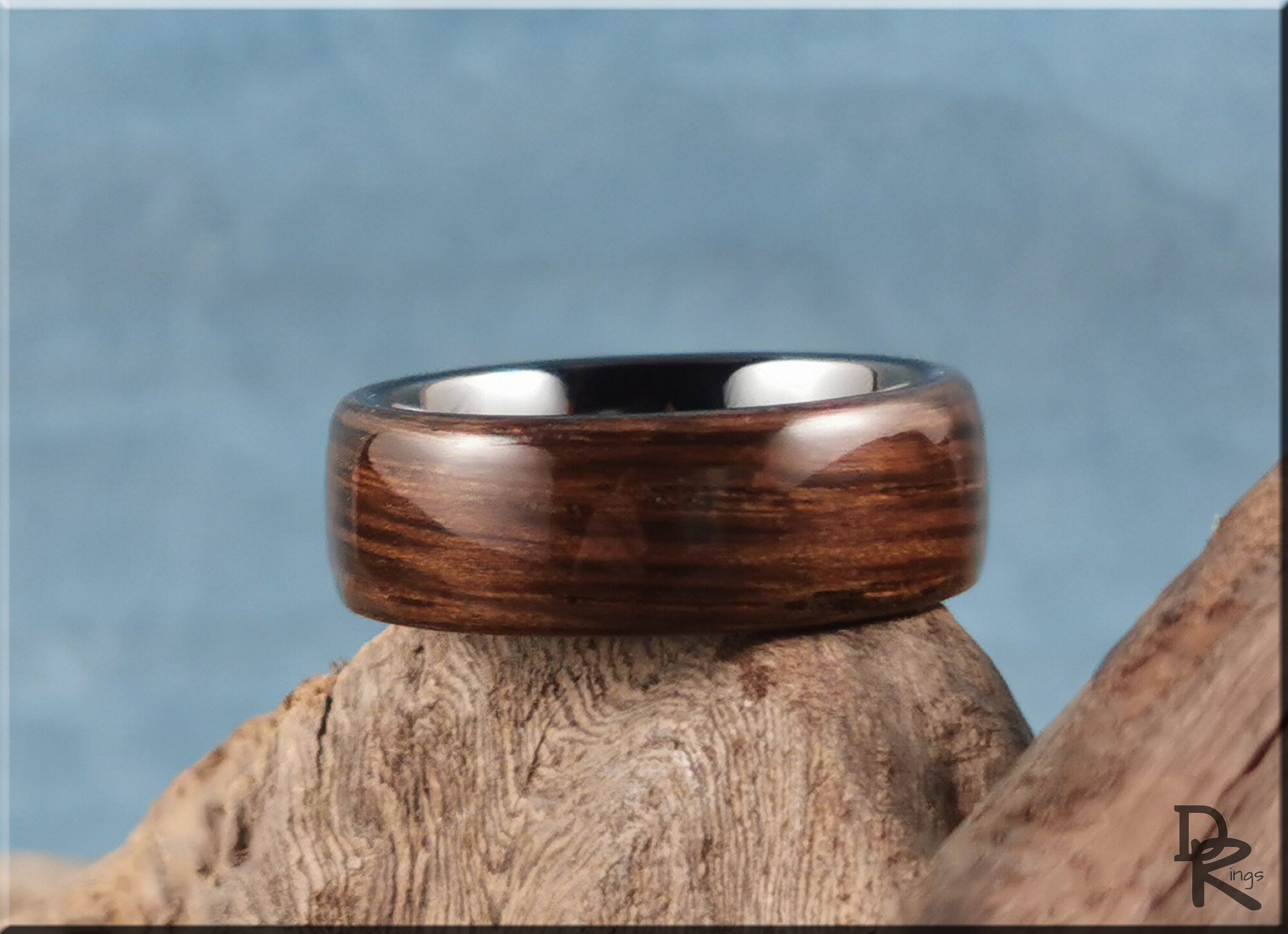 Bog oak ring on ceramic surface showcasing polished wood texture and silver interior by DR Rings