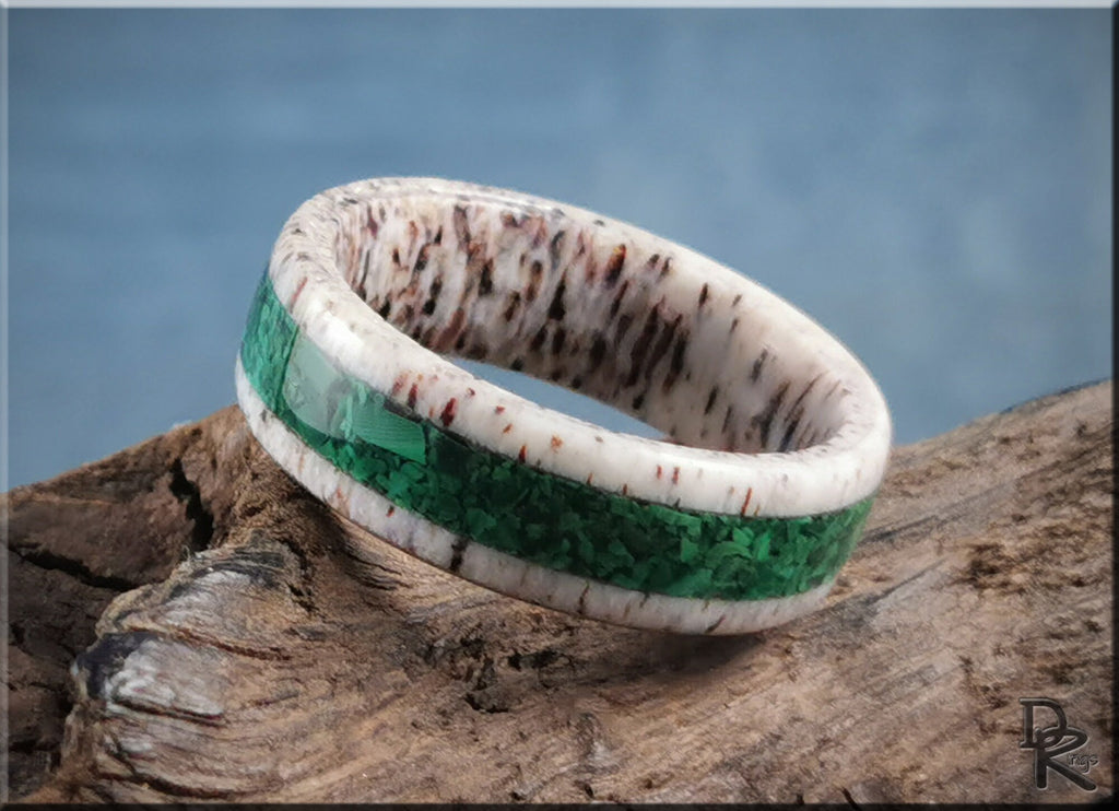 DR Rings handmade antler ring with a green inlay band placed on rustic wood background