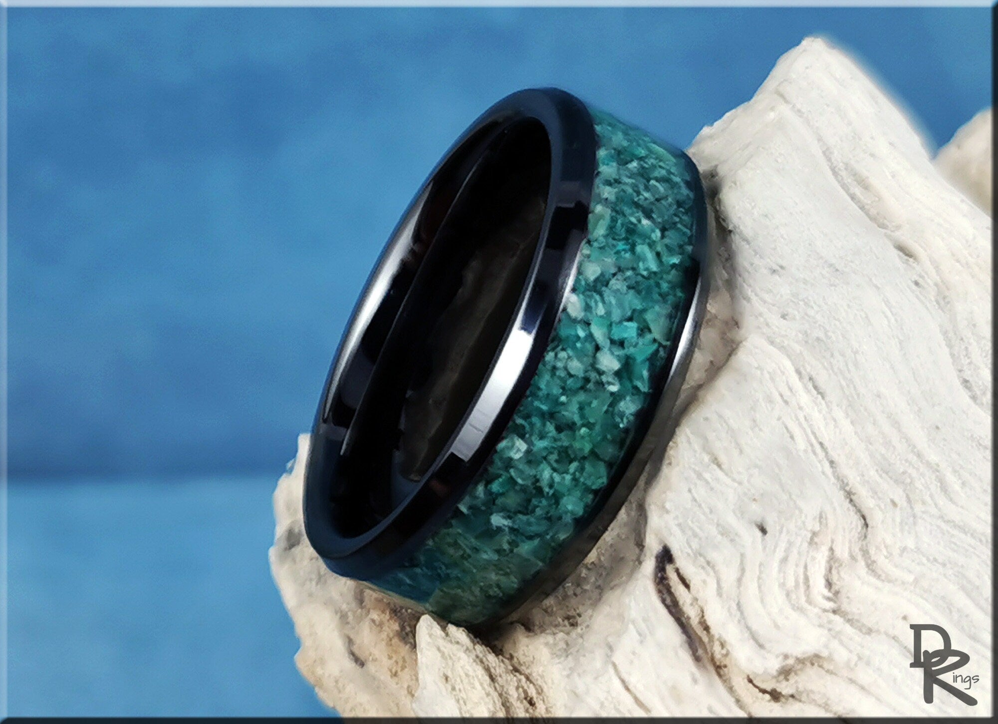 DR Rings black ceramic ring with inlay featuring textured blue-green stone detail on natural wood