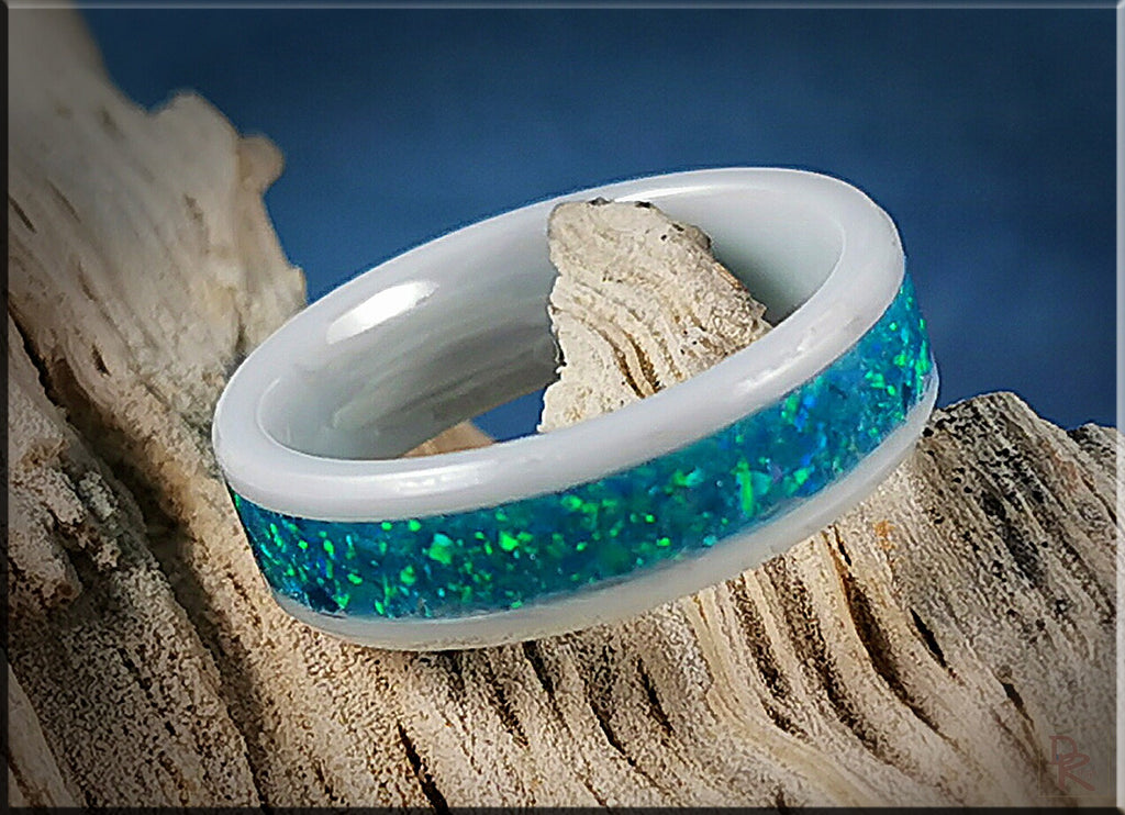 Ceramic ring with opal blue green inlay from DR Rings displayed on rustic wood background