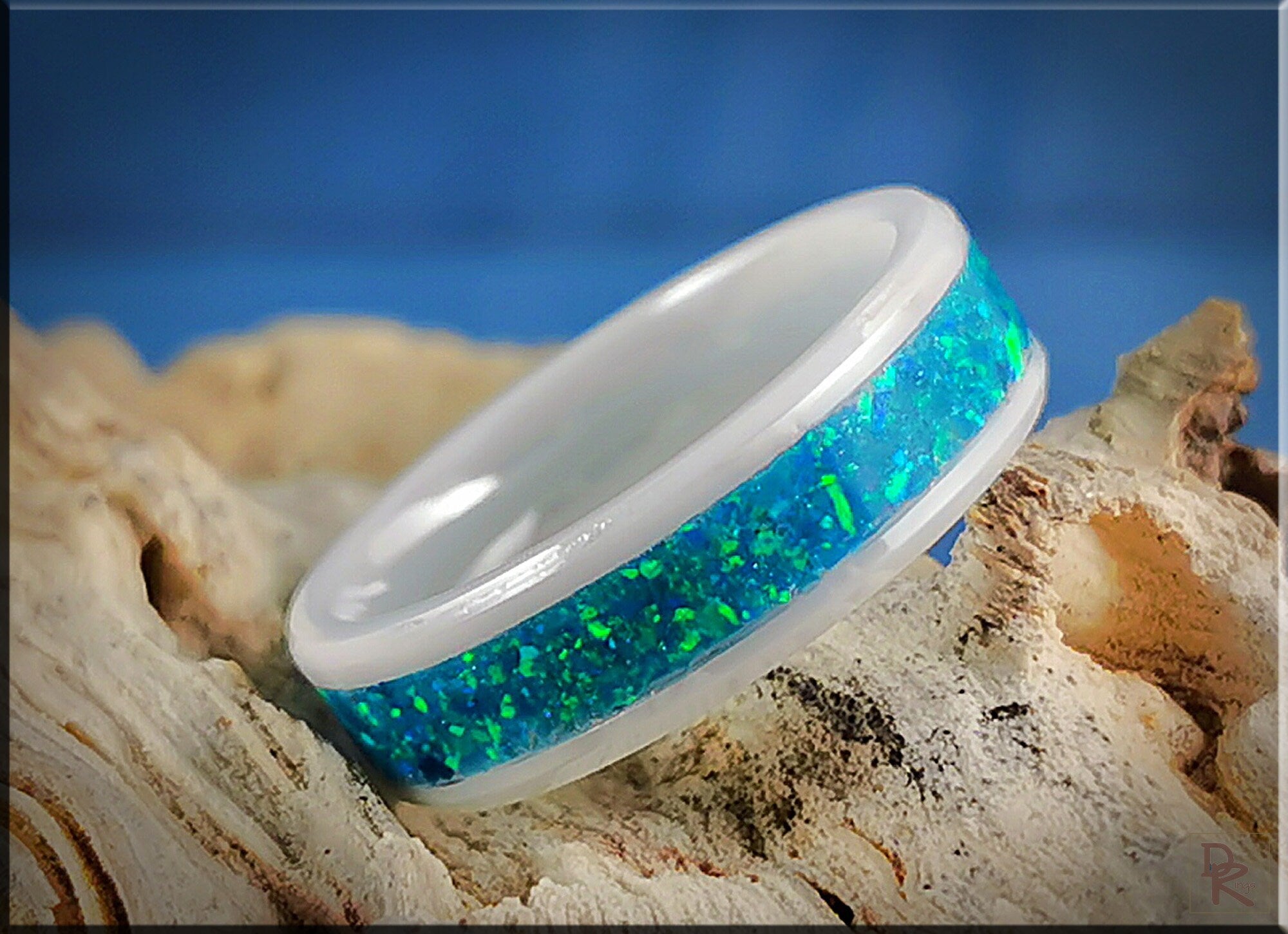 DR Rings ceramic ring with opal blue-green inlay on natural wood background