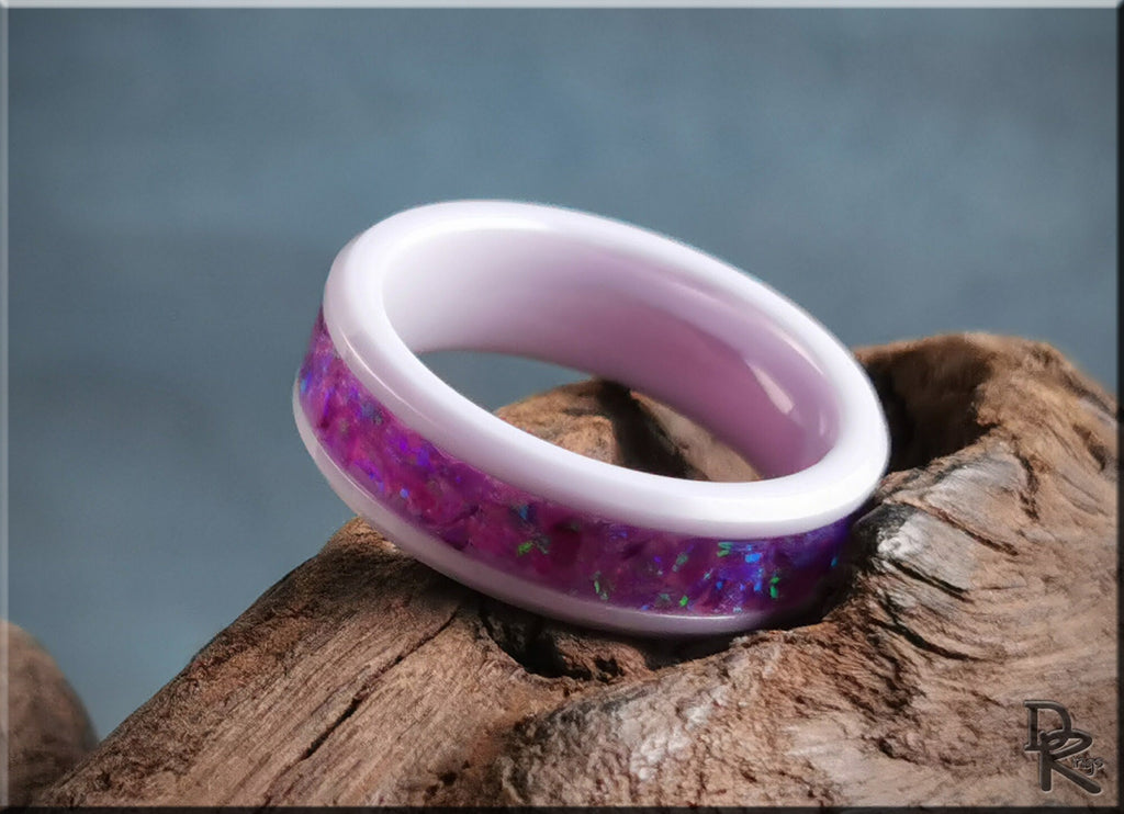 Ceramic ring with opal inlay featuring purple and pink hues by DR Rings on rustic wood