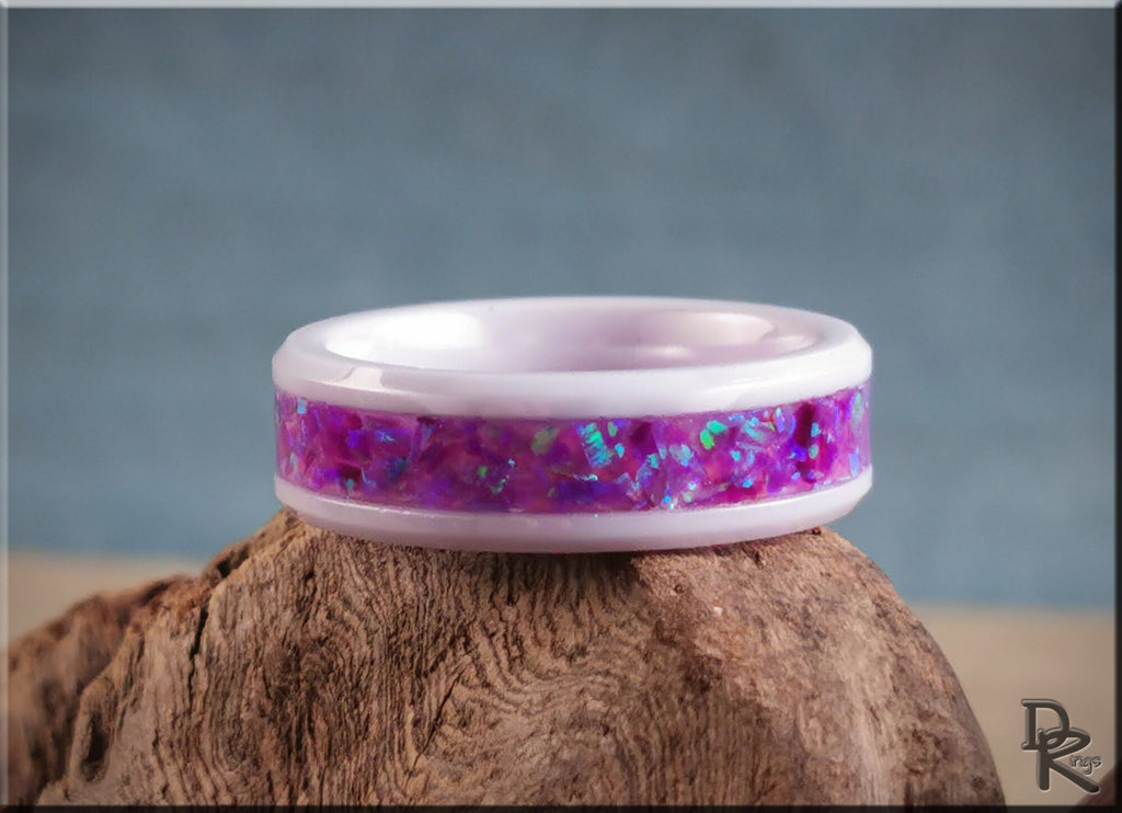 White ceramic ring with opal featuring a vibrant purple inlay from DR Rings on a wooden surface