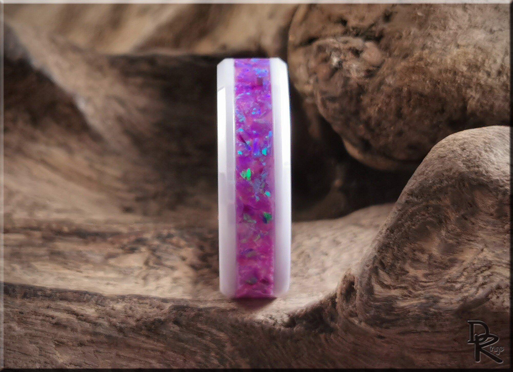 Ceramic ring with opal inlay featuring vibrant purple and blue hues displayed on textured wood