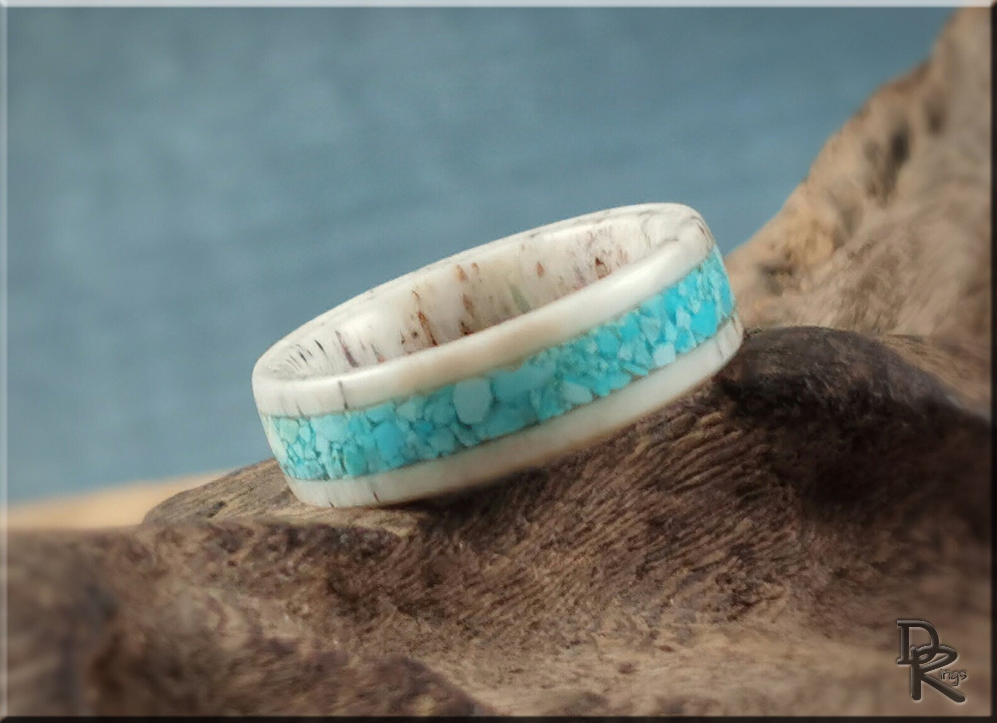Deer antler ring with turquoise inlay by DR Rings displayed on rustic wood background