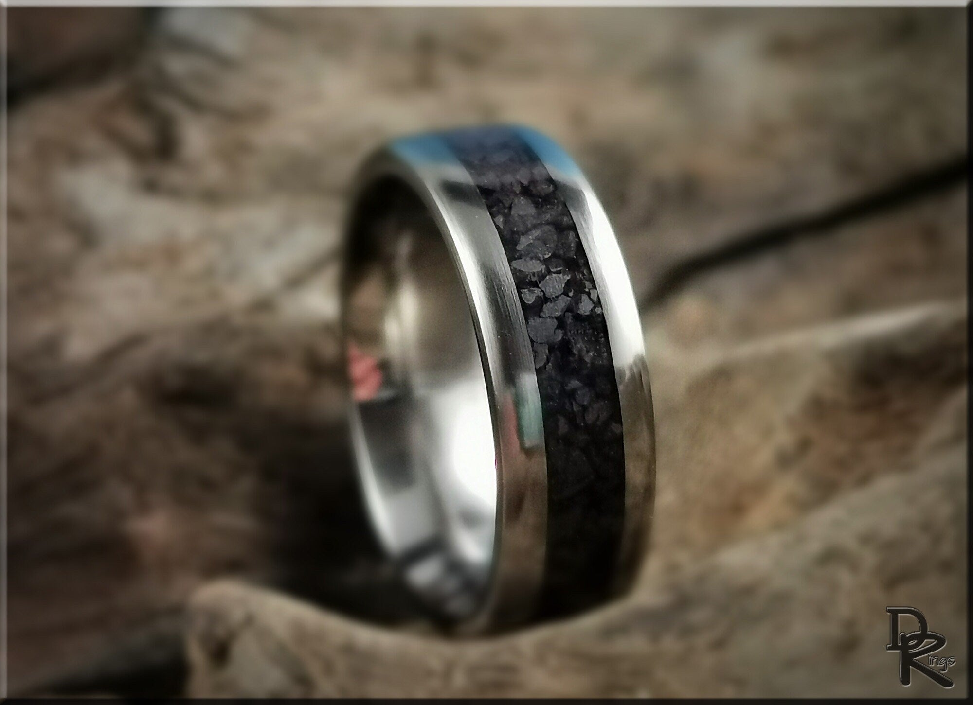 DR Rings titanium smart ring with black textured inlay and polished silver edges on rustic background