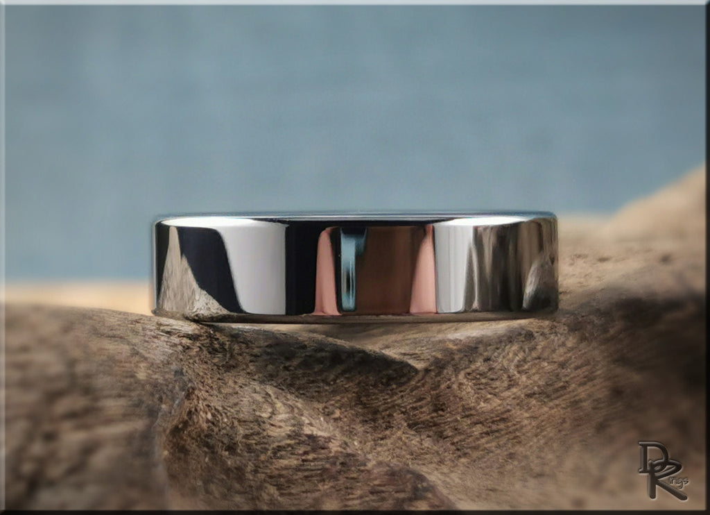 DR Rings polished tungsten ring carbide resting on textured wood surface with blue background