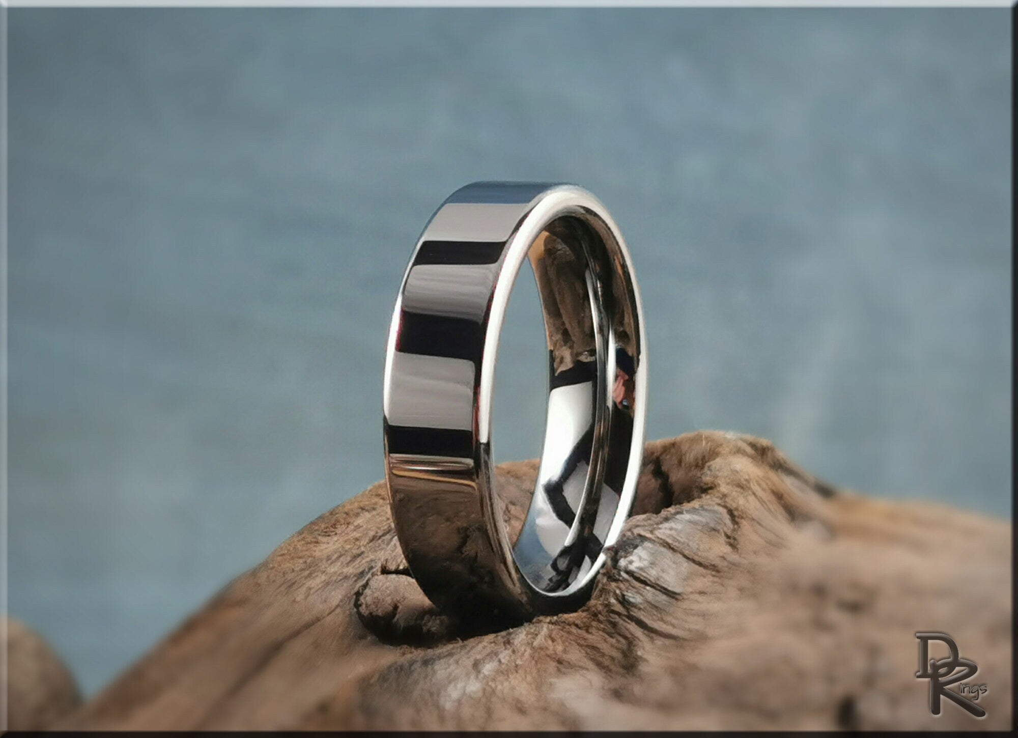 DR Rings polished tungsten ring carbide band with a sleek reflective surface on a natural wood background