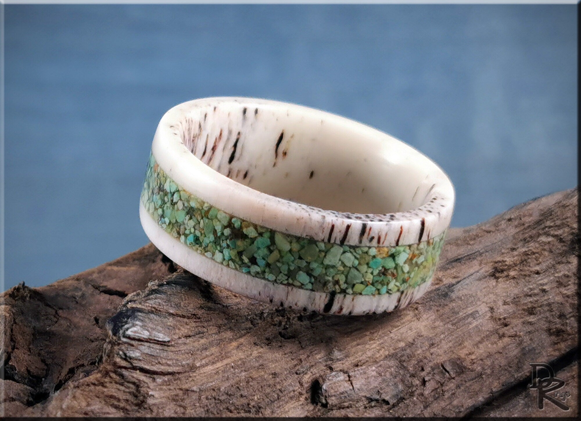 Deer antler ring with turquoise inlay resting on rustic wood background by DR Rings