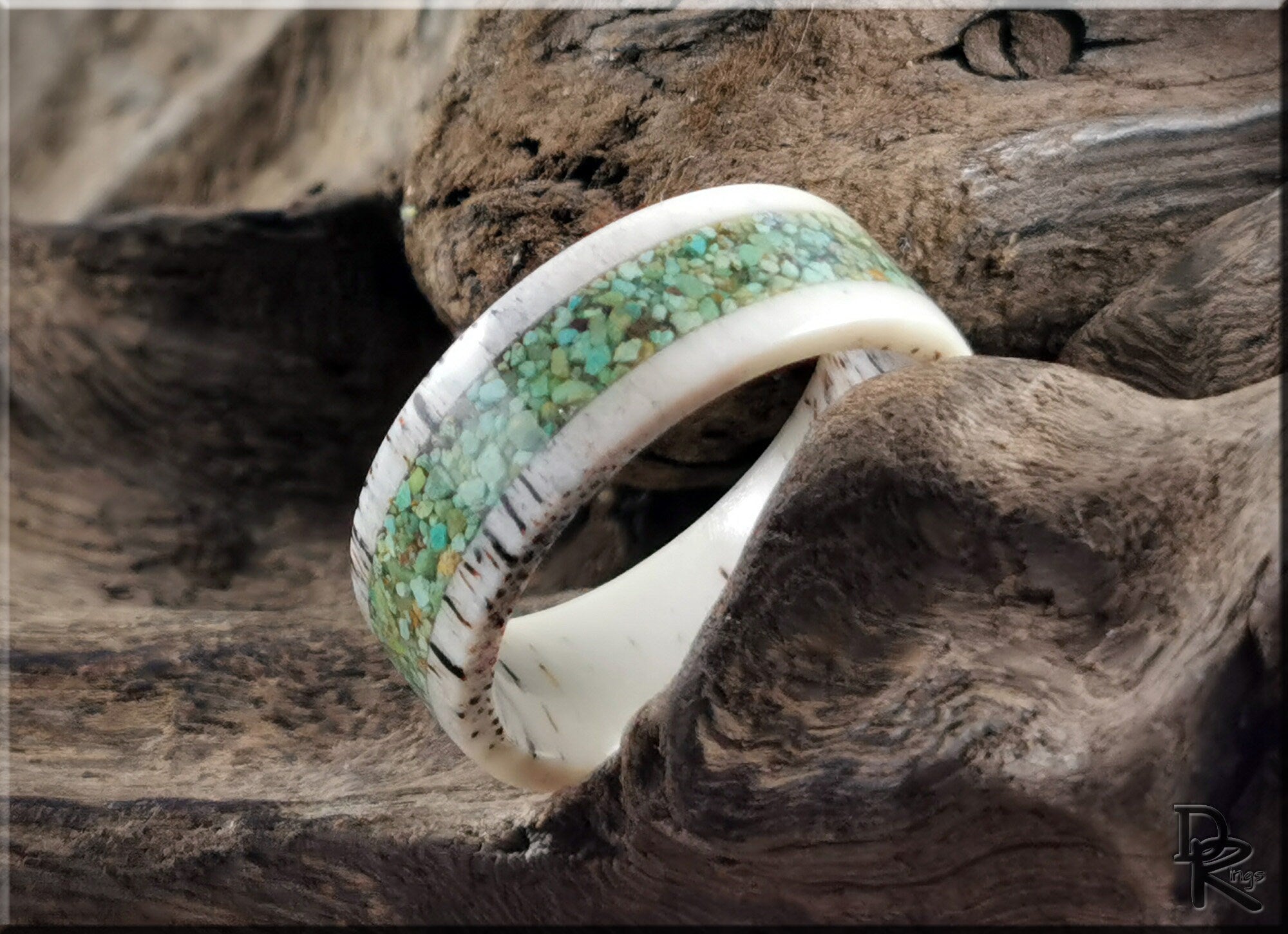 Deer antler ring with turquoise inlay featuring a blend of natural colors on rustic wood background
