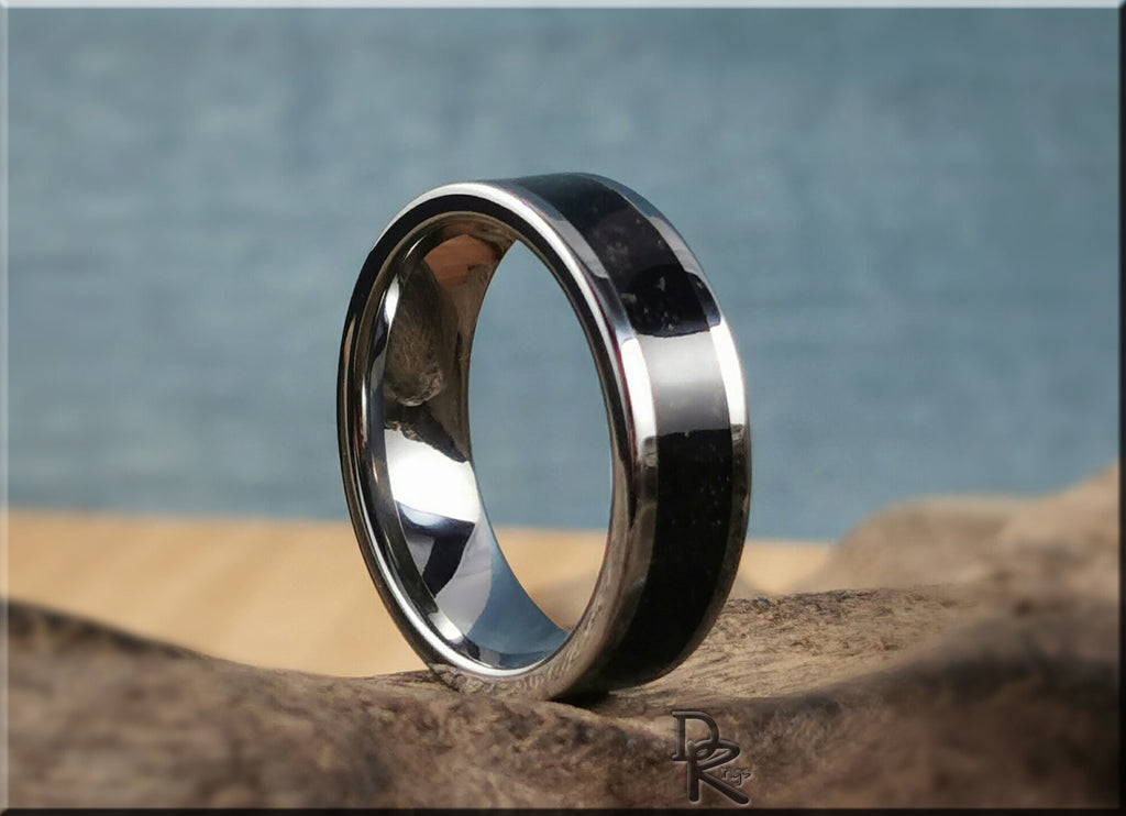Tungsten ring with shungite black inlay and polished silver edges on natural stone surface