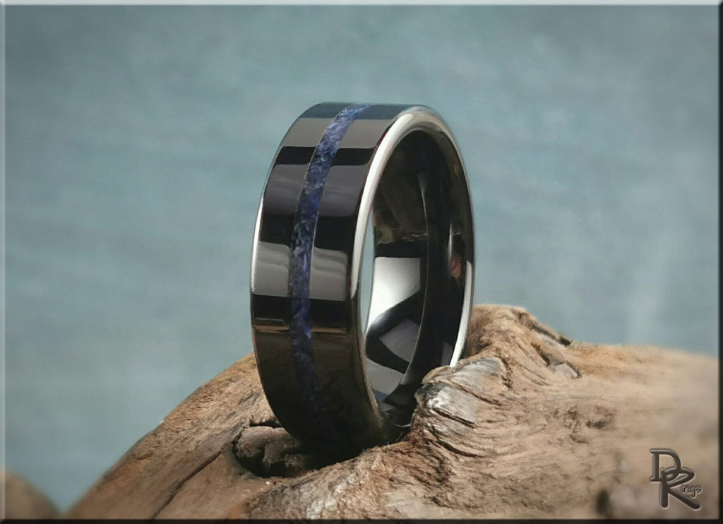 DR Rings black ceramic ring with blue inlay placed on textured wood background