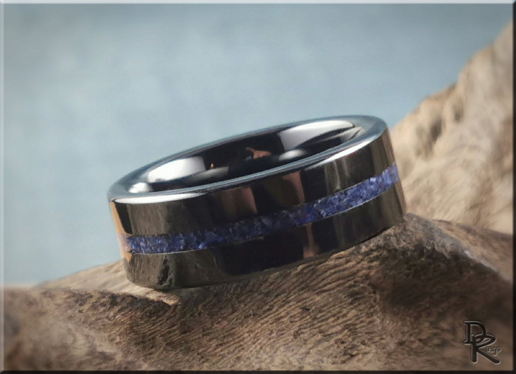 DR Rings black ceramic ring with a blue stone inlay resting on textured rock background