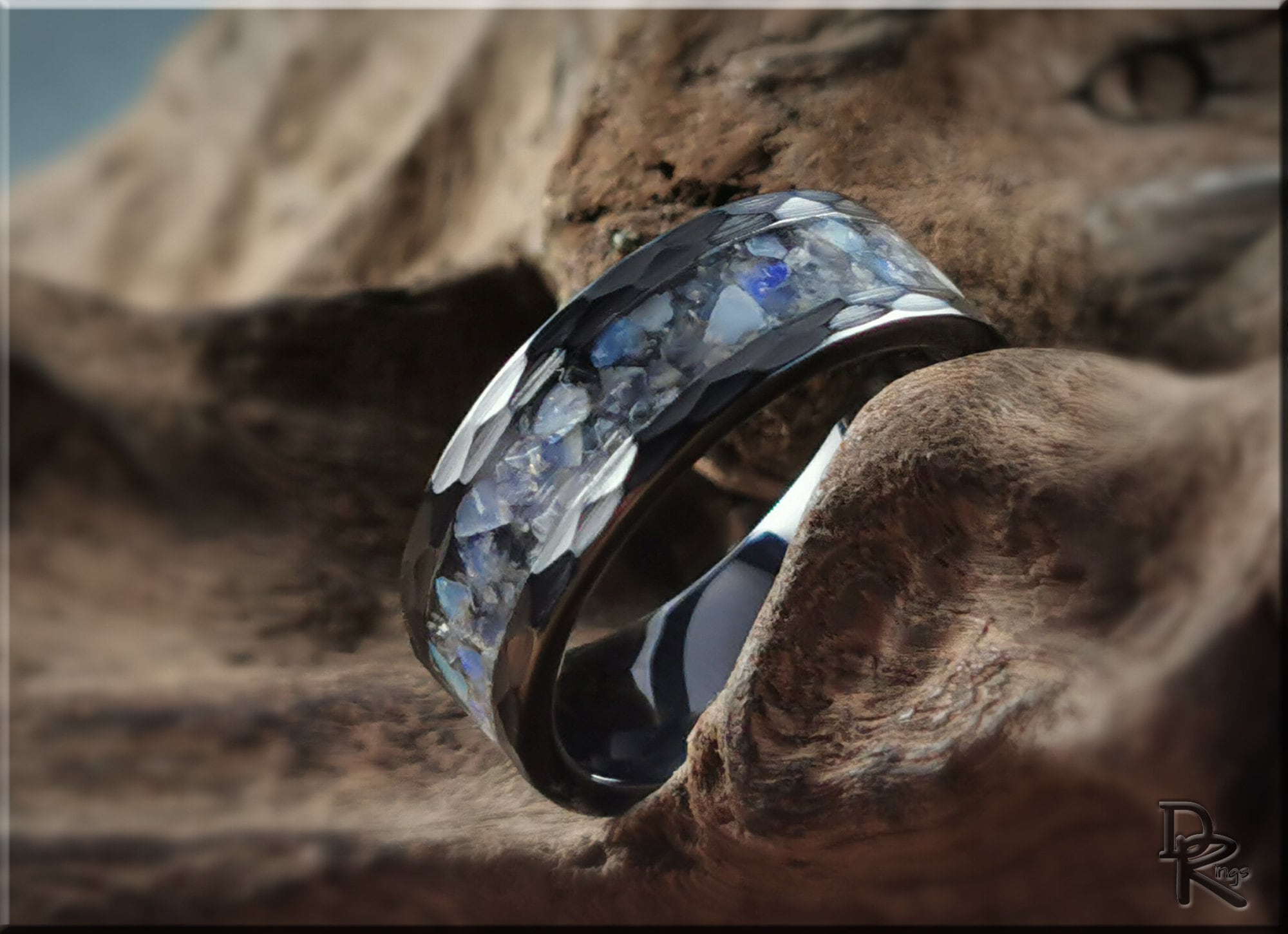 Hammered ceramic ring with inlay featuring blue and gray stone fragments on a textured surface