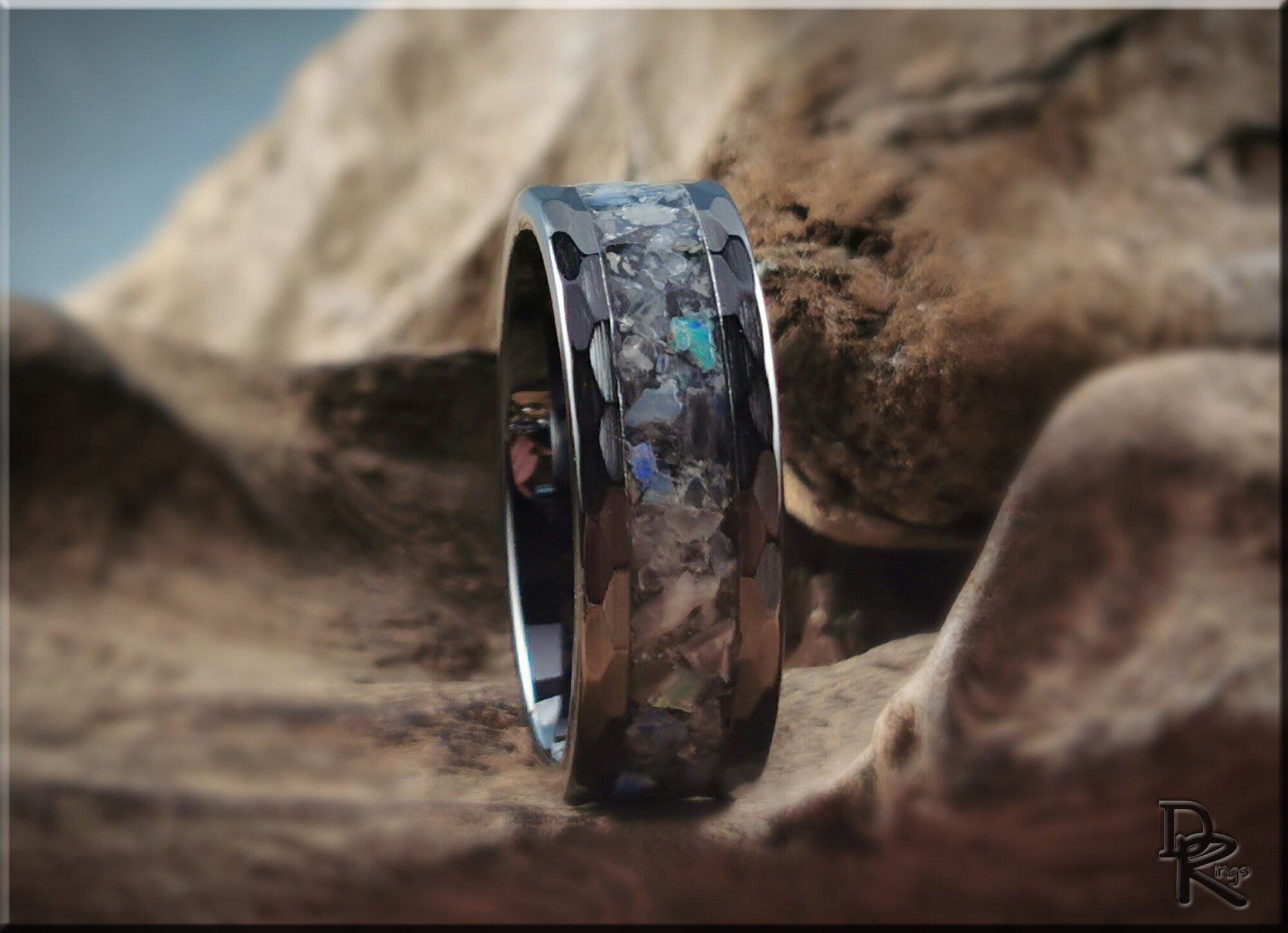 Hammered ceramic ring with inlay featuring colorful stone details by DR Rings on textured background