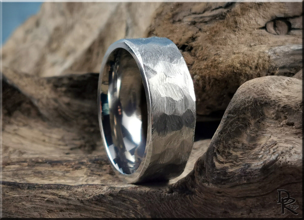 Hammered titanium ring with textured surface resting on rustic wooden background by DR Rings