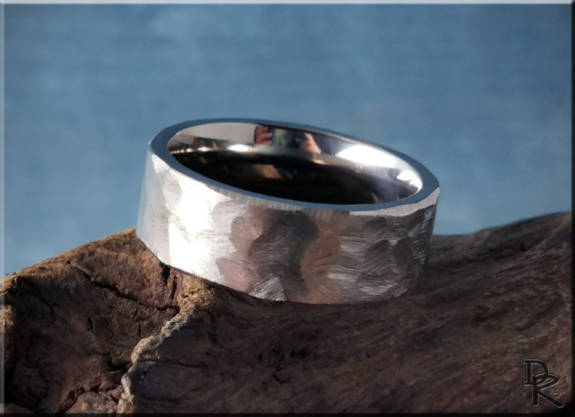 DR Rings hammered titanium ring with textured surface on a rustic wooden background