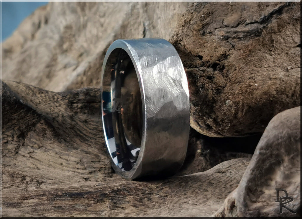 Hammered titanium ring by DR Rings with textured finish displayed on natural wooden surface