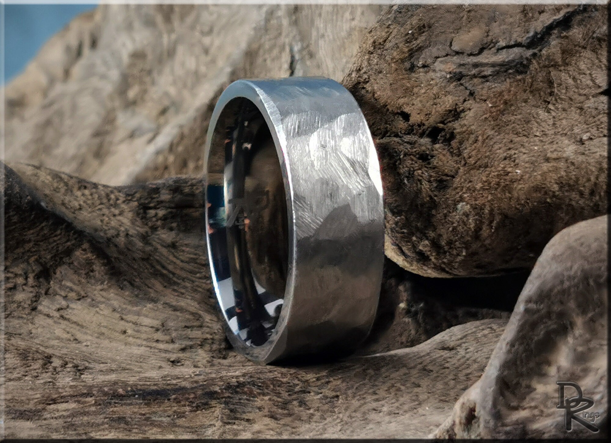 Hammered titanium ring by DR Rings with textured finish displayed on natural wooden surface