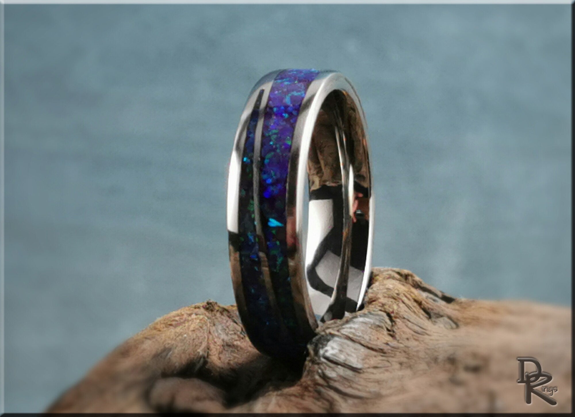DR Rings polished titanium ring with opal inlay featuring vibrant blue and purple hues on rustic wood