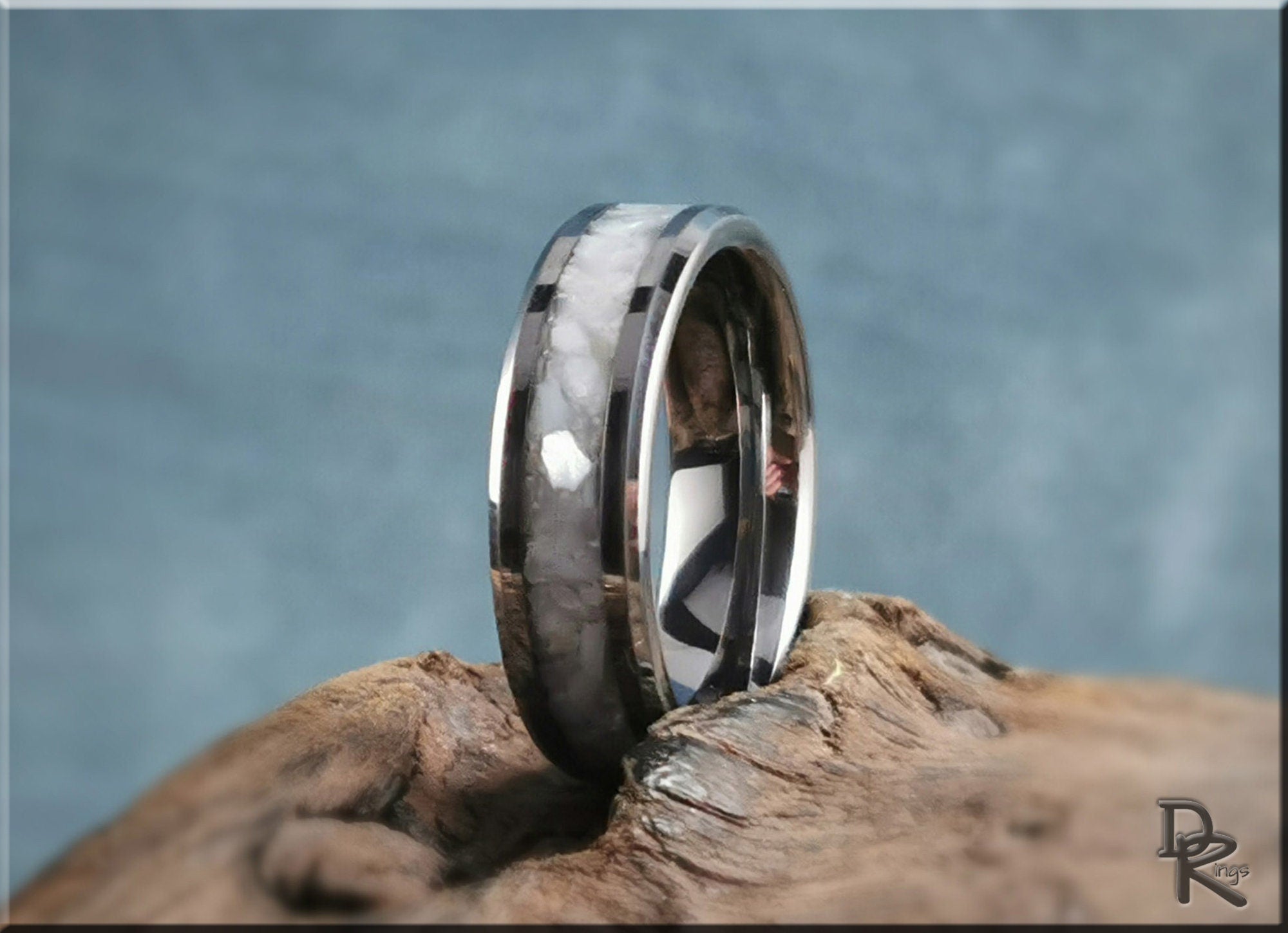 DR Rings tungsten ring with pearl inlay displayed on a textured wooden surface