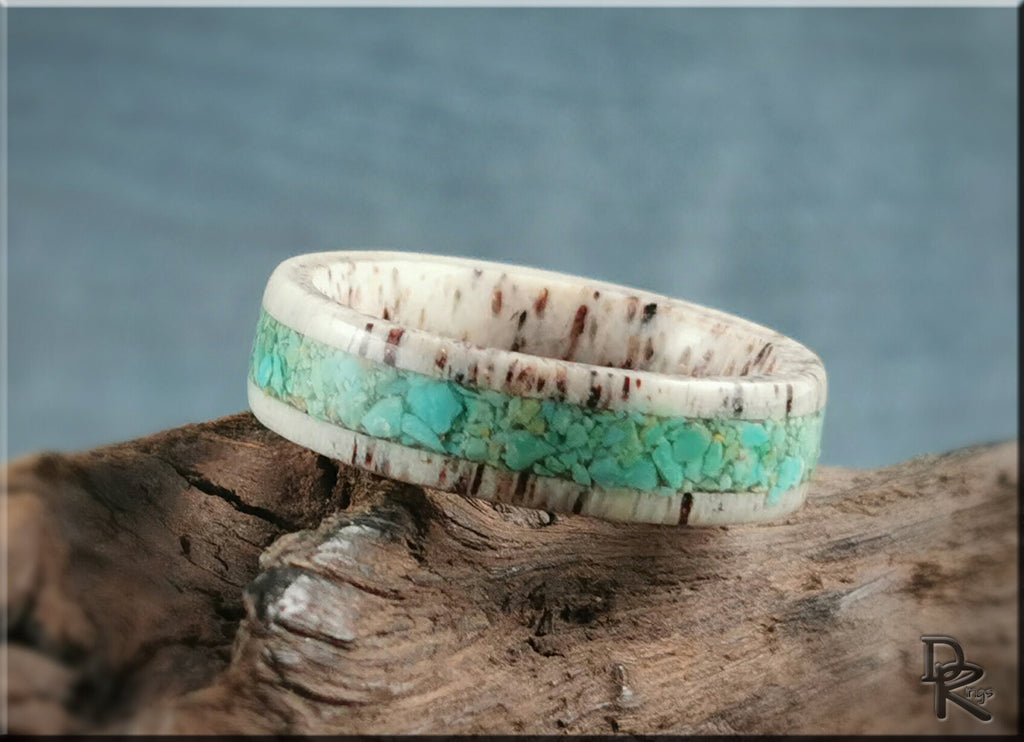 Antler ring with turquoise inlaid band featuring natural turquoise stones on rustic wood background