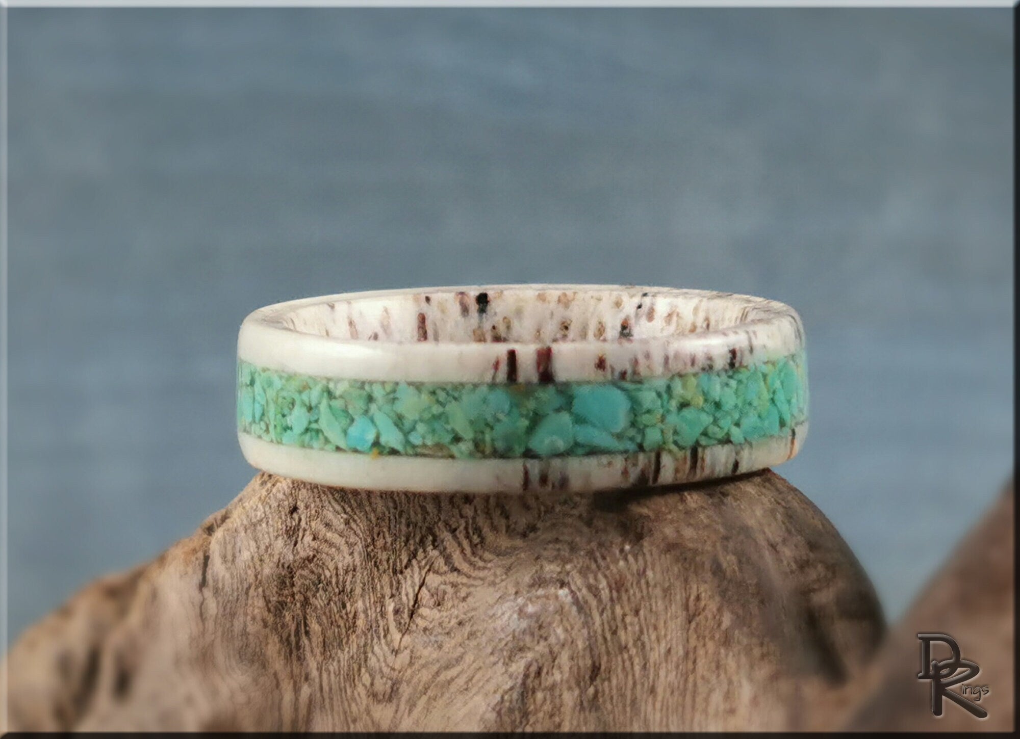 Antler ring with turquoise inlay by DR Rings on a wooden surface with a blue background