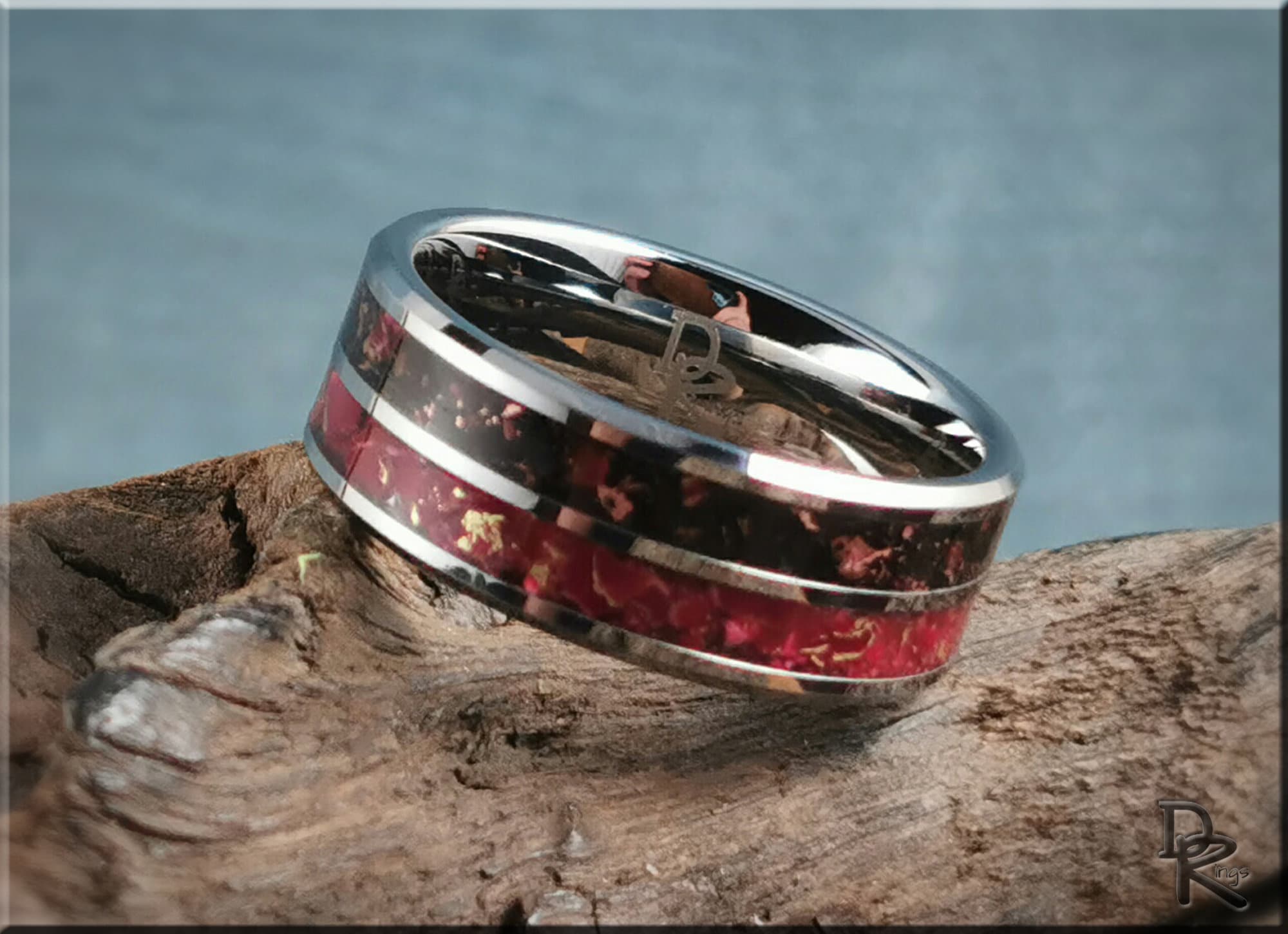 DR Rings tungsten carbide ring with inlay featuring red and black detailed design on wood background
