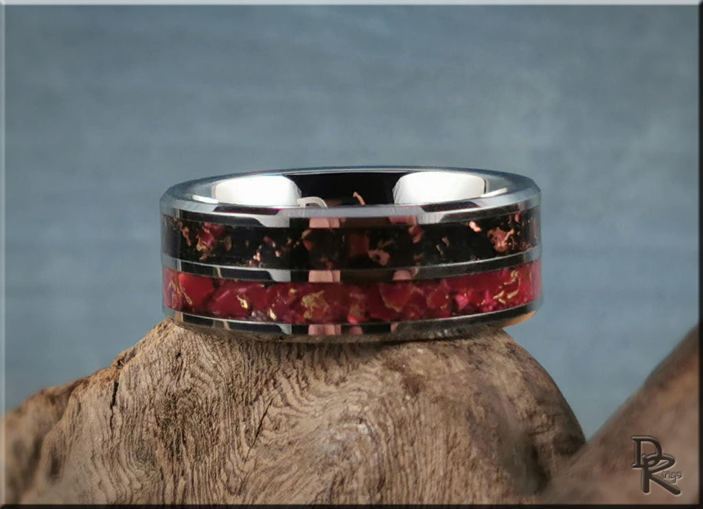 Tungsten carbide ring with inlay featuring black and red stone design on wooden surface