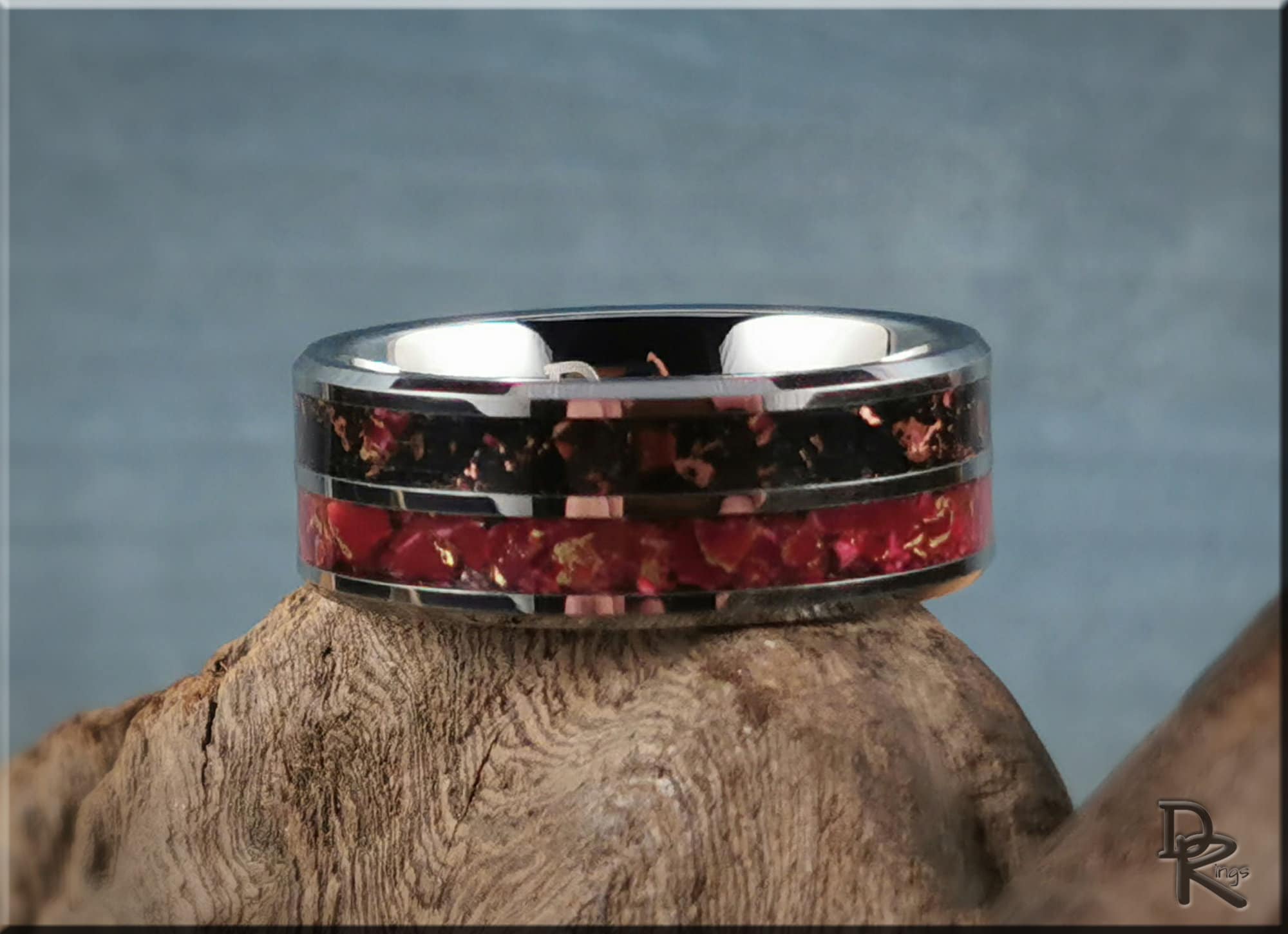 Tungsten carbide ring with inlay featuring black and red stone design on wooden surface