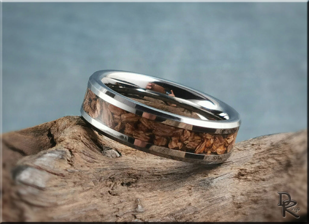 Tungsten ring with dinosaur bone inlay featuring polished silver edges on rustic wood background