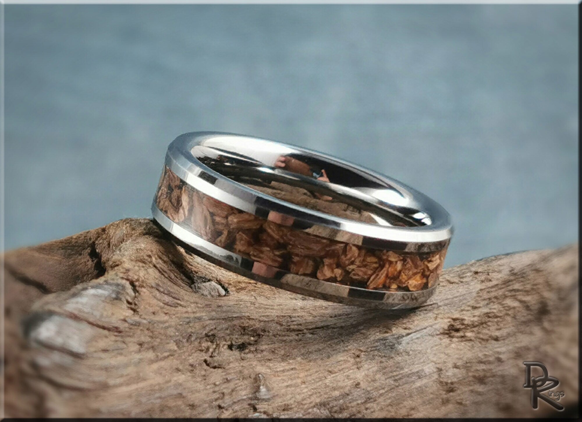 Tungsten ring with dinosaur bone inlay featuring polished silver edges on rustic wood background