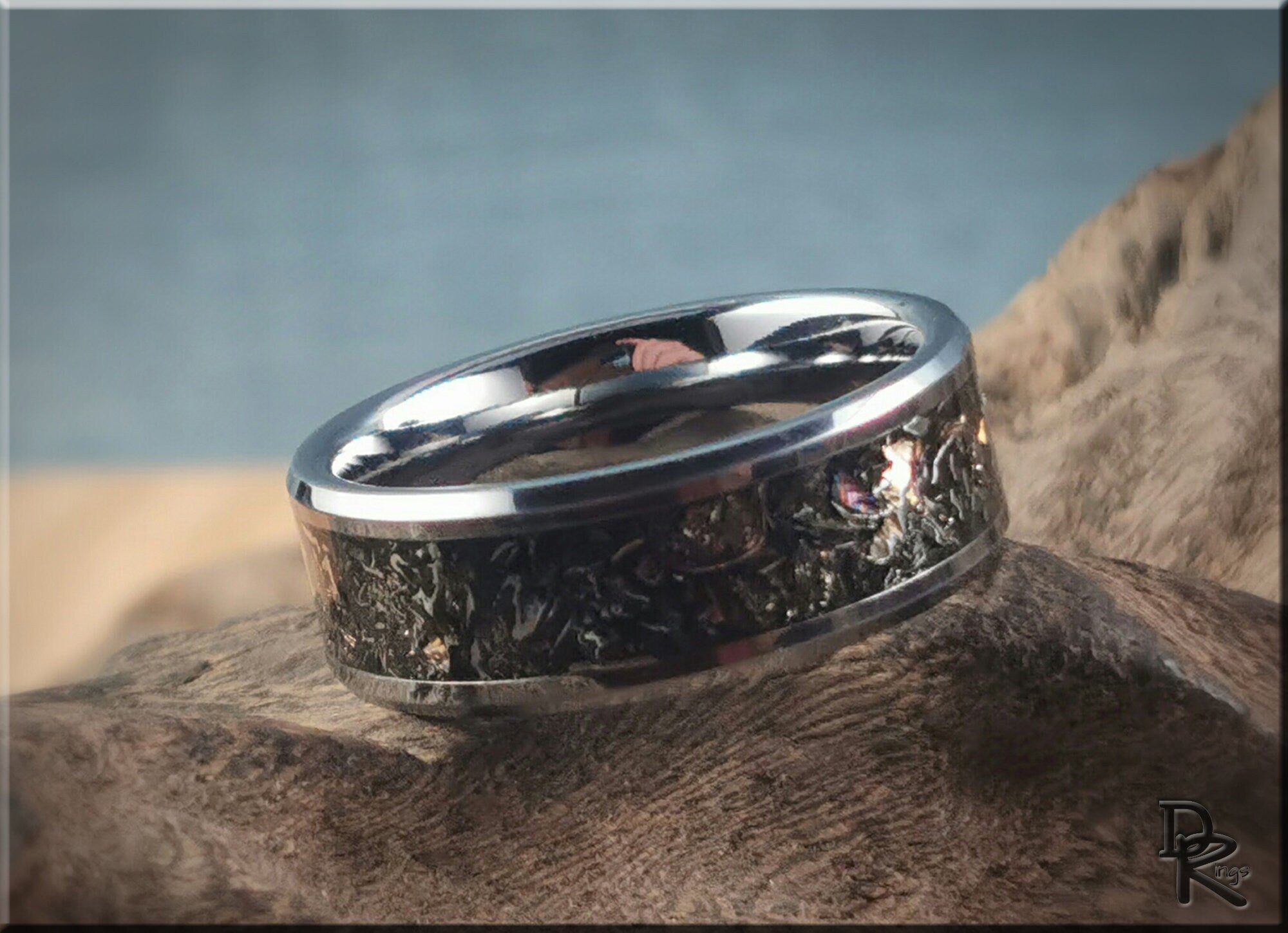 Tungsten ring with meteorite inlay by DR Rings resting on textured surface with blurred background