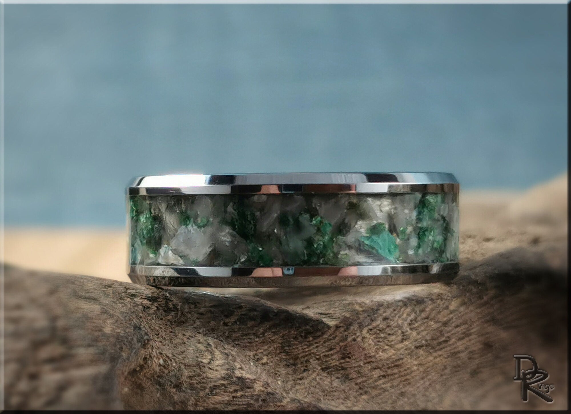 DR Rings tungsten ring with moonstone featuring green and white stone inlay on a natural wood surface