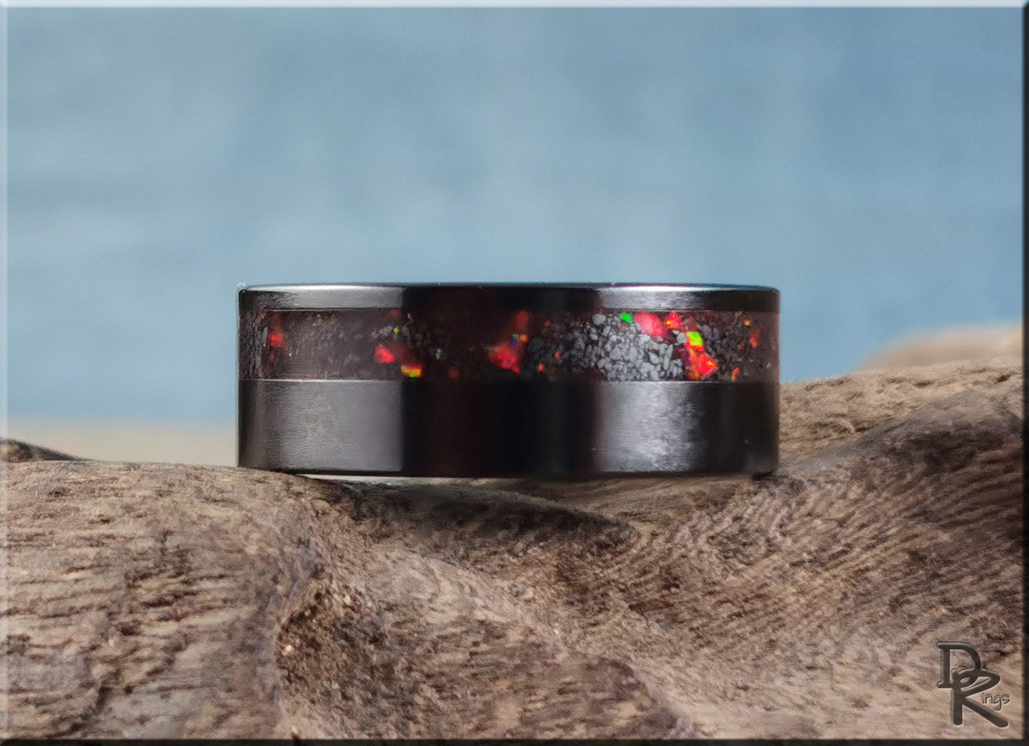 DR Rings black band ring opal inlay with vibrant red and orange flashes on natural wood background