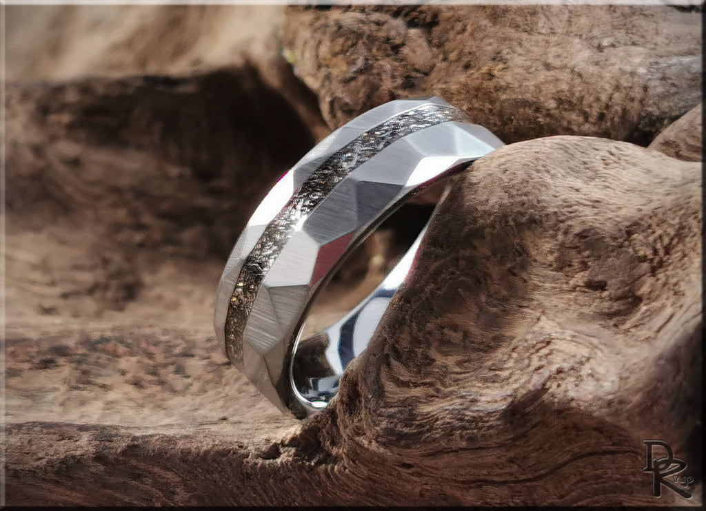 Hammered tungsten carbide ring with meteorite inlay resting on textured wood background